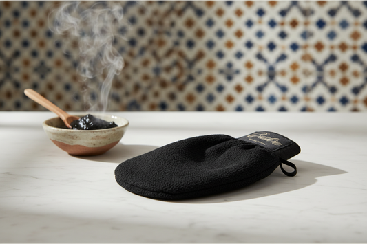 Moroccan kessa exfoliating glove on marble surface with black soap for traditional hammam ritual