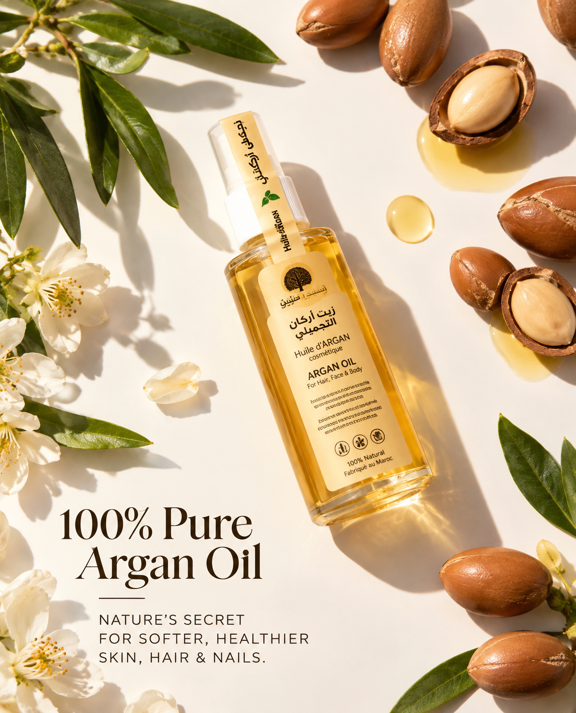 Bashra Beauty argan oil arranged with argan nuts, green leaves, white blossoms, and golden oil on a cream background with the text 100% Pure Argan Oil.
