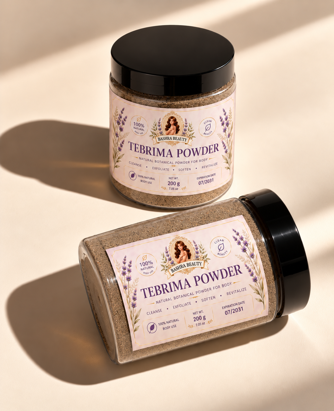 Two Bashra Beauty Tebrima Powder jars, one upright and one lying diagonally, on a warm cream surface with natural sunlight and shadows.