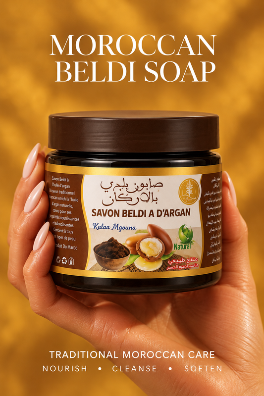 Traditional Moroccan beldi soap with argan oil in a dark jar, held in a hand against a warm amber background.